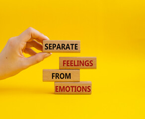 Feelings and Emotions symbol. Concept word Separate Feelings from Emotions on wooden blocks. Beautiful yellow background. Doctor hand. Psychology and Feelings and Emotions concept. Copy space