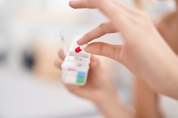 Young blonde woman holding pills at home
