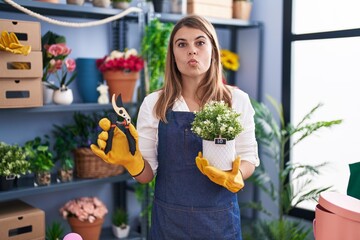 Young hispanic woman working at florist shop looking at the camera blowing a kiss being lovely and sexy. love expression.