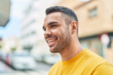 Young hispanic man smiling confident looking to the side at street