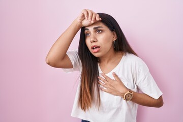 Fototapeta premium Young arab woman standing over pink background touching forehead for illness and fever, flu and cold, virus sick