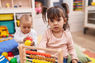 Adorable boy and girl playing with abacus sitting on floor at kindergarten