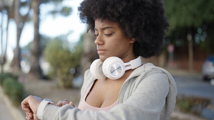 African american woman wearing sportswear using stopwatch at park © Krakenimages.com