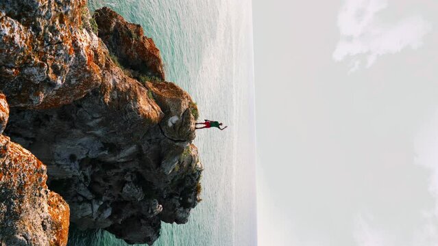 The traveler stands on a rock, waves his hand and photographs the seascape. Travel and Photo concept. 4K