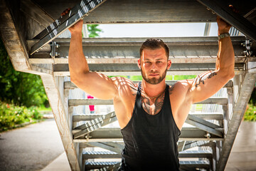 Muscular attractive athletic man in city under stairs