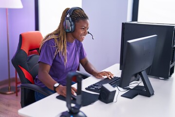 African american woman streamer playing video game using computer at gaming room