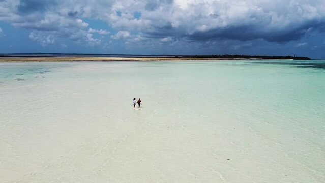 pareja andando tranquilamente con el mar tranquilo en un banco de arena