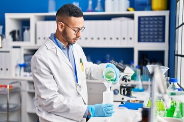 African american man scientist pouring liquid on bottle at laboratory