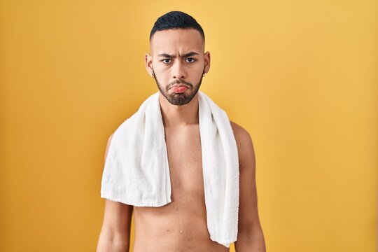 Young hispanic man standing shirtless with towel depressed and worry for distress, crying angry and afraid. sad expression.