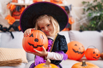 Adorable blonde girl wearing witch costume having halloween party at home