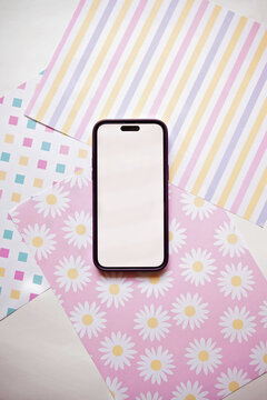 Mobile phone with blank screen on assorted colourful paper