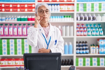 Middle age woman with tattoos working at pharmacy drugstore mouth and lips shut as zip with...