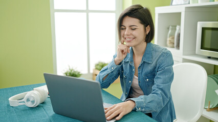 Young caucasian woman using laptop sitting on the table at home