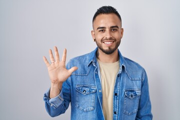 Young hispanic man standing over isolated background showing and pointing up with fingers number...