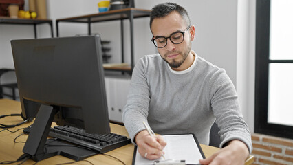 Hispanic man business worker using computer writing on document at office