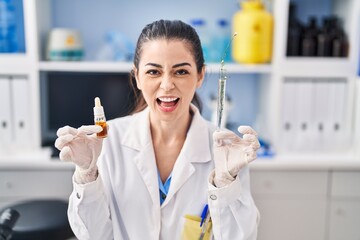 Young woman doing weed oil extraction at laboratory angry and mad screaming frustrated and furious, shouting with anger. rage and aggressive concept.