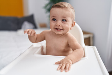 Adorable caucasian baby sitting on highchair at home