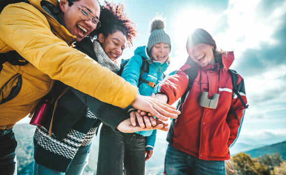 Multiracial happy hikers stacking hands outside - Group of happy climbers with backpacks having fun on trekking tour - Sport life style concept with guys and girls celebrating success together