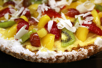 Creamy cake with fresh strawberries, peaches and kiwi, selective focus. Sweet cream dessert with grated white chocolate