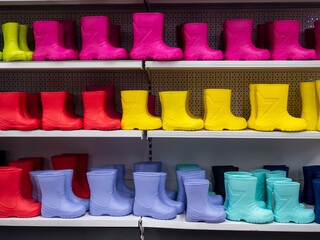 Shelves in the store with rubber boots . Boots of different colors, a large selection for children and adults. All the colors of the rainbow. Shoes in rainy weather.
