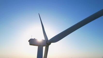 Aerial close up shot of wind mills turbine rotating by the wind and generating renewable green energy. Closeup of a wind turbine during golden hour sunset. Energy alternative and environment ecology.