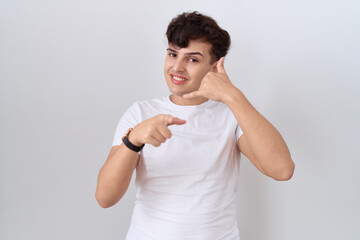 Young non binary man wearing casual white t shirt smiling doing talking on the telephone gesture...