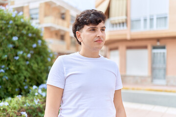 Non binary man looking to the side with serious expression at park