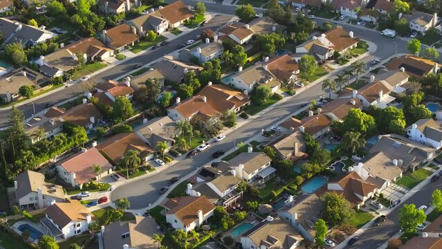 Los Angeles suburban housing district area in USA. Aerial drone shot of residential American homes in quiet neighborhood at golden hour. Beautiful green suburb aerial at scenic sunset 4K California