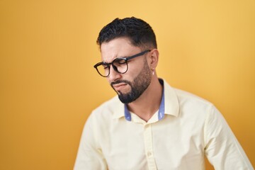 Hispanic young man wearing business clothes and glasses with hand on stomach because indigestion, painful illness feeling unwell. ache concept.