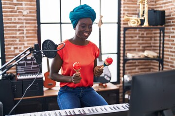 Young african american woman musician playing maracas at music