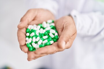 Young bald man pharmacist holding pills at pharmacy