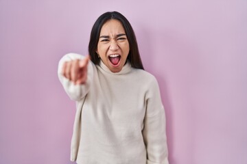 Fototapeta premium Young south asian woman standing over pink background pointing displeased and frustrated to the camera, angry and furious with you