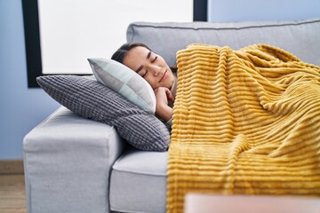 Young hispanic woman lying on sofa sleeping at home