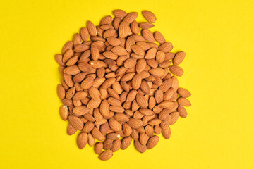 Handful of almonds yellow background.