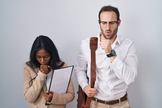 Interracial business couple wearing glasses feeling unwell and coughing as symptom for cold or bronchitis. health care concept.