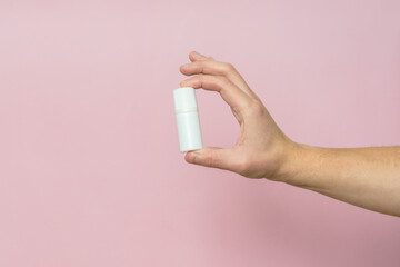 Drops bottle for eye or ear in hand on pink background. Pharmaceutical product. Copy space.