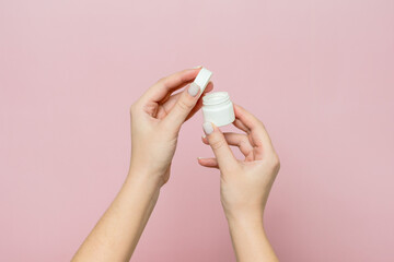 White jar or bottle with cream (ointment) in woman's hands. Facial care, bottle with cosmetic product