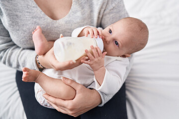 Adorable caucasian baby sucking feeding bottle at bedroom