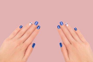 Female hands with blue nail design. Glitter blue manicure with rhinestones. Female model hands with...