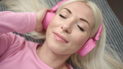 Young blonde woman listening to music sleeping on sofa at home
