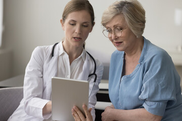 Female therapist holding digital tablet show health test check up result, share treatment plan to...