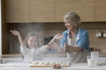 Happy multi generational family, grandmother and granddaughter have fun, prepare pastries,...