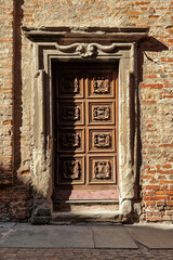 Old wooden door and brick wall in Alba, Italy.