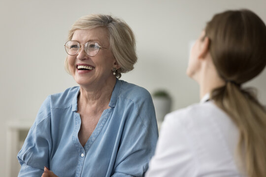 Mature woman clinic patient laughs during visit in clinic, get professional medicare, receive consultation looks optimistic feels happy. Eldercare, medicine, professional medical services, insurance