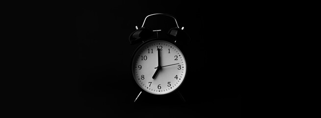 Black alarm clock on black background.