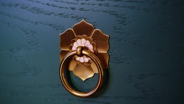 Close-up of door ring. Creative. Beautiful flower pattern with ring on front door. Ring for knocking on door in retro style with beautiful pattern