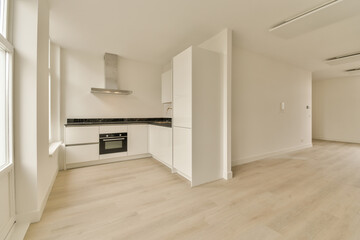 an empty room with wood flooring and white cupboards on either side of the room, there is a stove in the corner