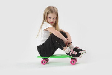 Fototapeta na wymiar Studio portrait of beautiful blonde little girl with skateboard
