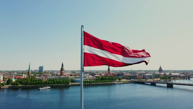 Huge Latvian flag flutters in the wind with Riga old town in the background in Latvia. Beautiful summer day.