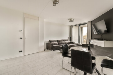 a living room with black and white furniture on the floor in front of a large flat screen tv mounted to the wall